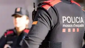 Un agente de Mossos d'Esquadra de espaldas con una compañera difuminada al fondo, imagen para preparar las oposiciones de Mossos 2026.