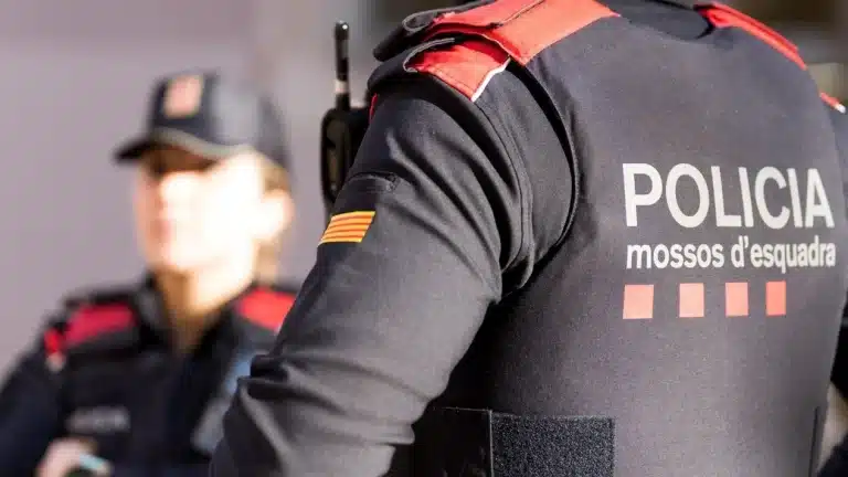 Un agente de Mossos d'Esquadra de espaldas con una compañera difuminada al fondo, imagen para preparar las oposiciones de Mossos 2026.